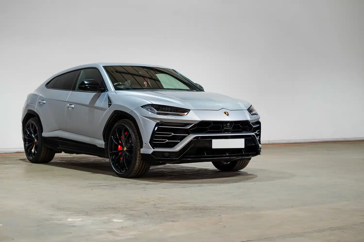 A grey, 2021 Lamborghini Urus V8 Auto, facing forwards, in front of a white wall, in a warehouse
