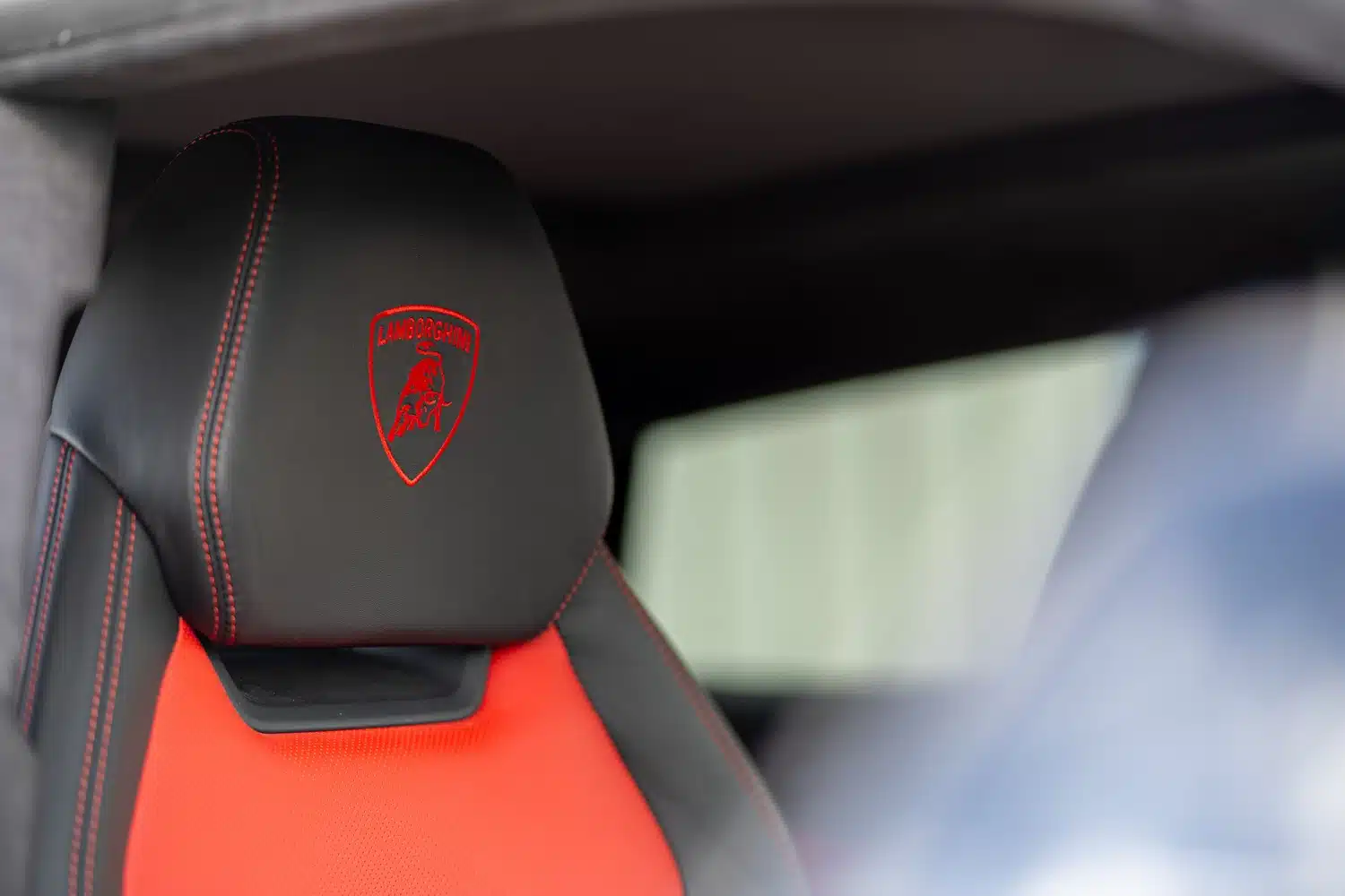 Close up of the Lamborghini logo stitched in red on a black headrest within a 2021 Lamborghini Urus V8 Auto