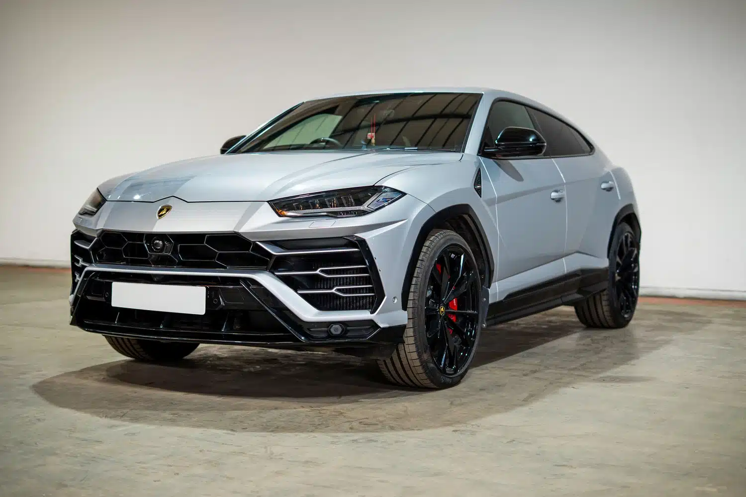 A grey, 2021 Lamborghini Urus V8 Auto, facing forwards, in front of a white wall, in a warehouse